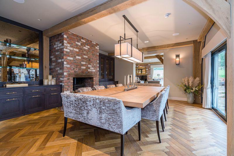 Elegant dining room with oak beams, brick fireplace, parquet flooring and velvet chairs – Kings Interiors, Oxfordshire interior design.