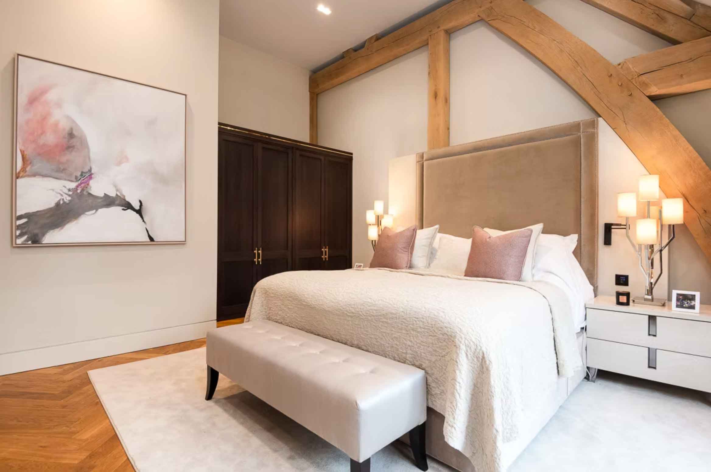Luxury bedroom with oak beams, upholstered headboard and soft neutral tones – Kings Interiors, Oxfordshire interior design.