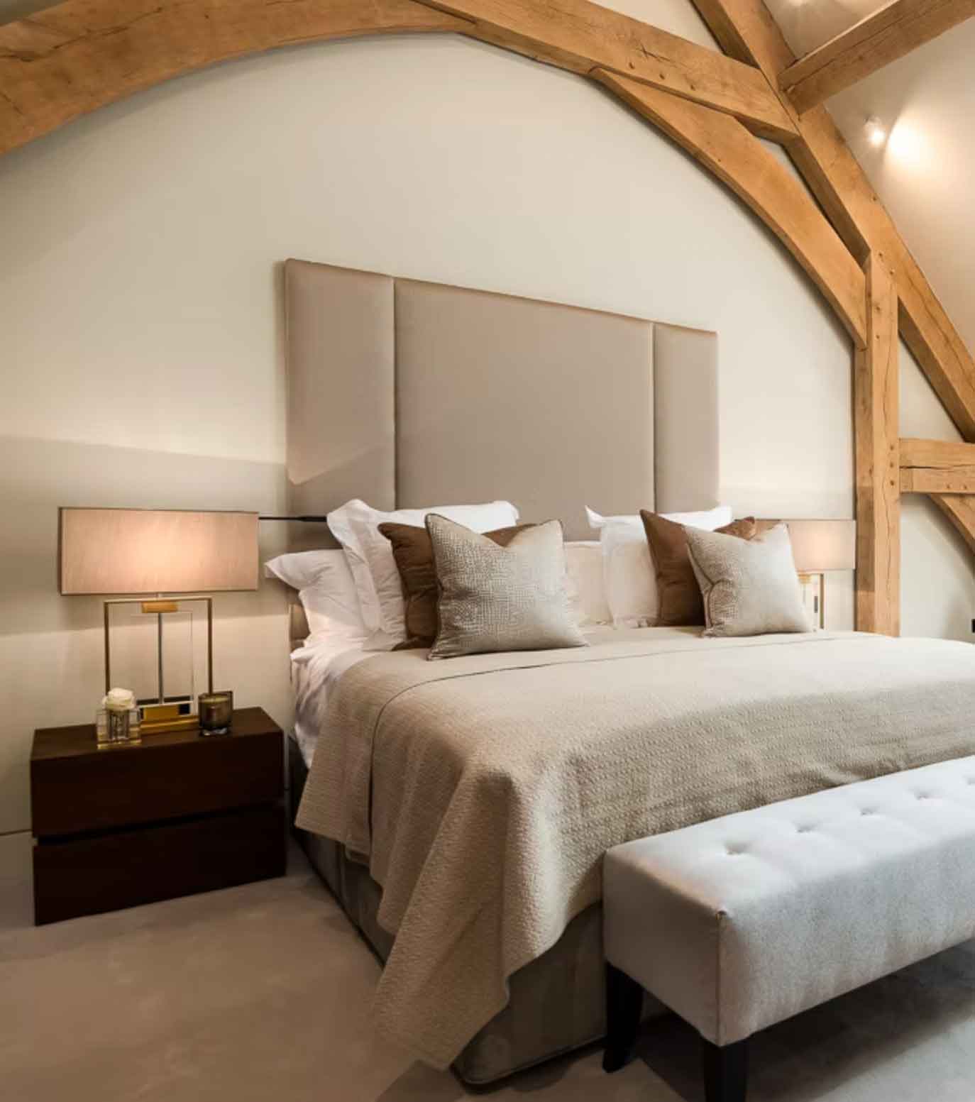 Luxury bedroom with oak beams, upholstered headboard and warm neutral tones – Kings Interiors, Oxfordshire interior design.