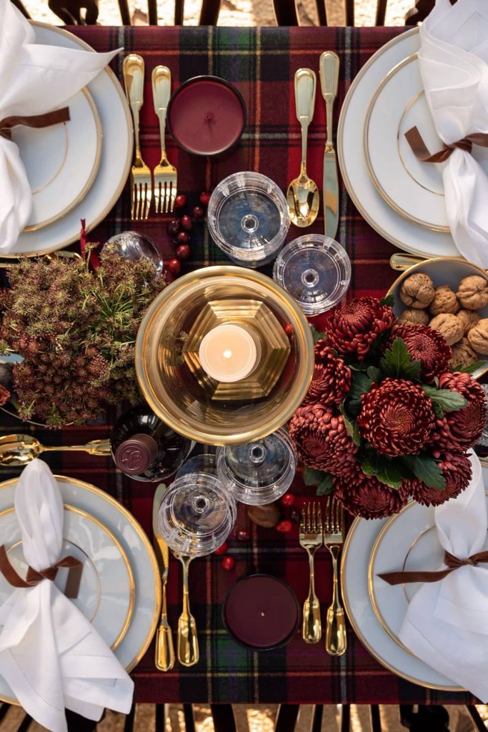Elegant holiday table setting with gold cutlery and plaid linen
