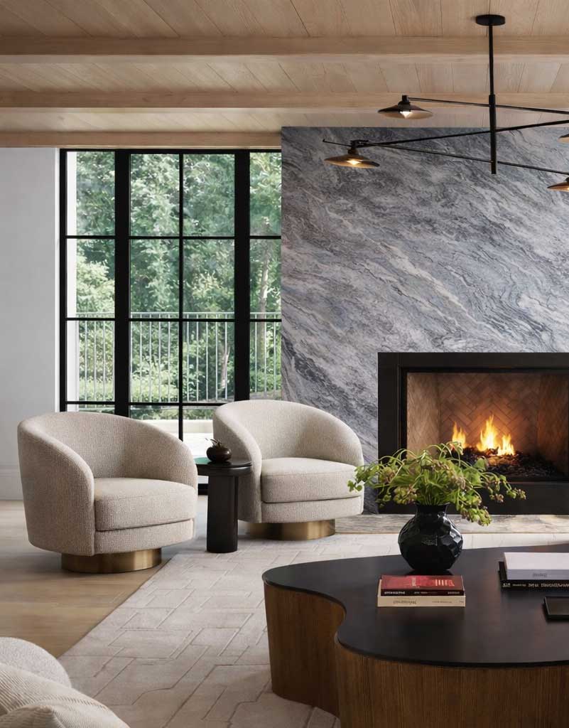 Modern living room interior with two cream upholstered chairs, side table, large window, and contemporary stone fireplace